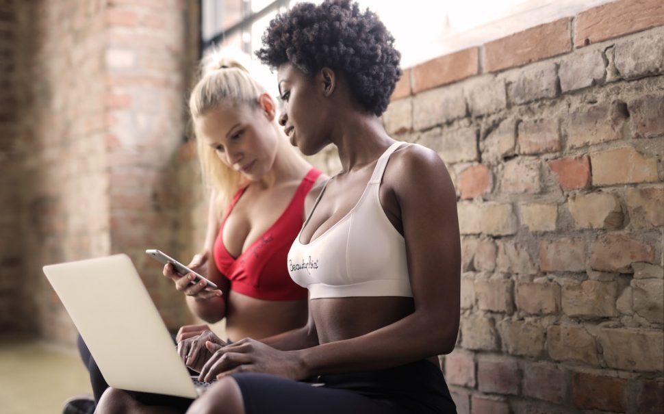 two women in fitness gear on a laptop