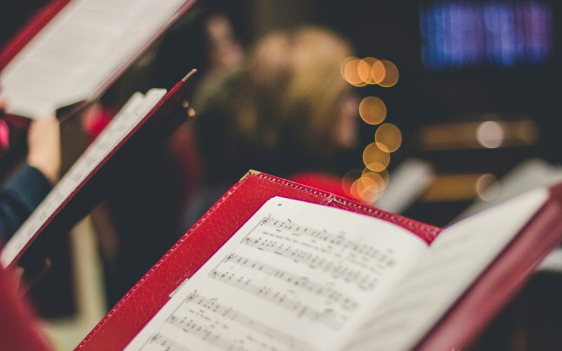 Picture of a red music sheet book with a blurred Christmas tree in the back
