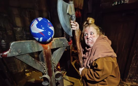 A woman at the London Dungeon taking an axe to a football
