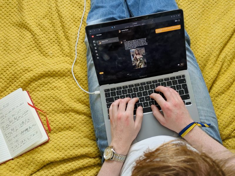 A person with a laptop on their lap, texting an AI girlfriend