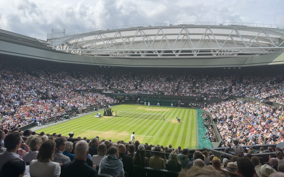 An image of Wimbledon centre court, filled with people. The court is in the centre of the photo