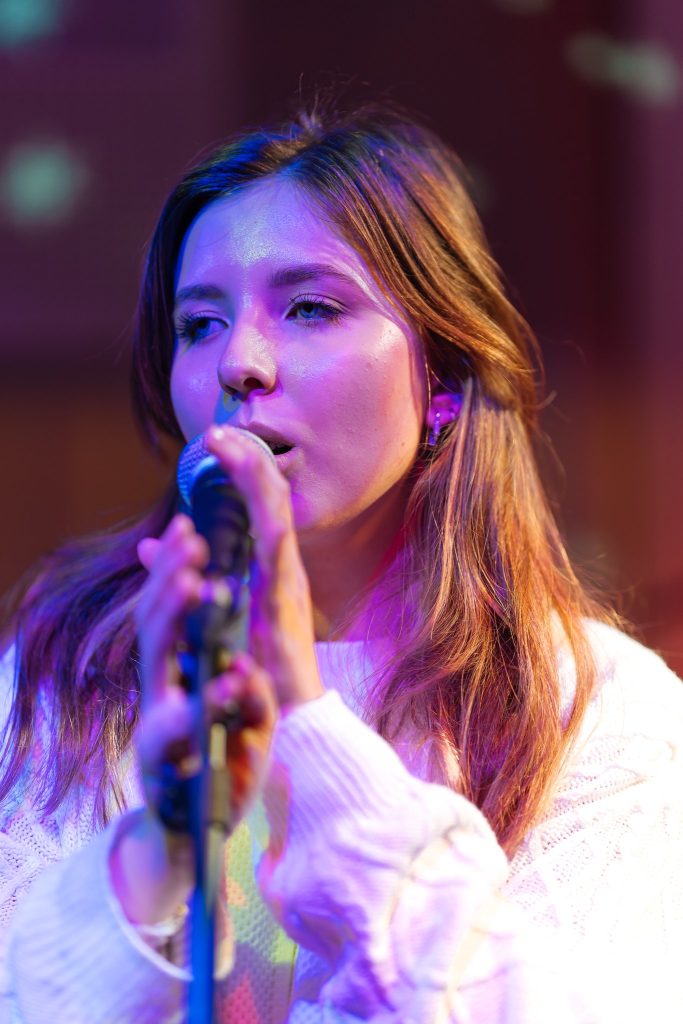 A woman, Ruxy, stood at a microphone and singing