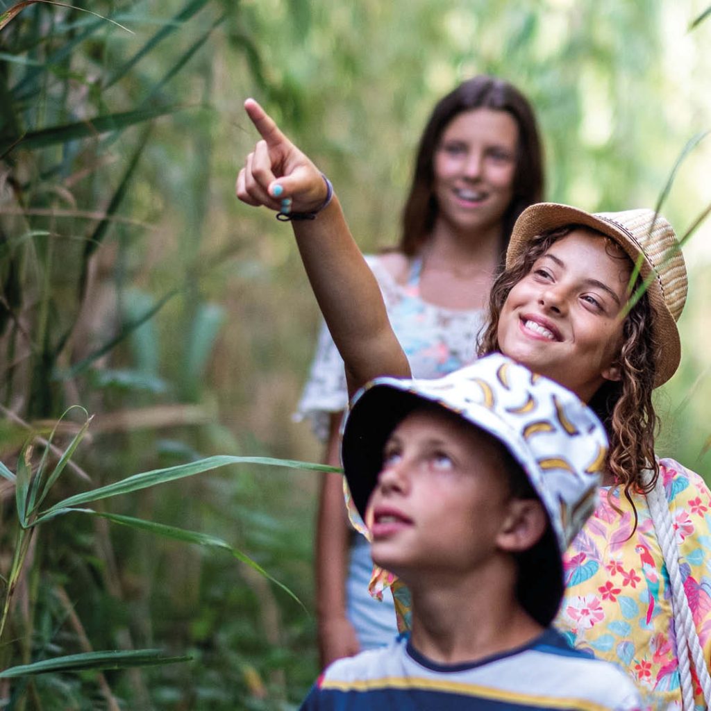 A family surrounded by vegetation, with one pointing at some off camera