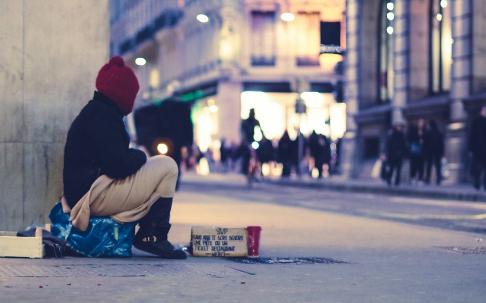 A homeless person sitting on the pavement