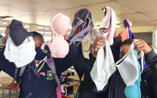 School girls hold up their new bras from ZABRA to the camera, covering their faces