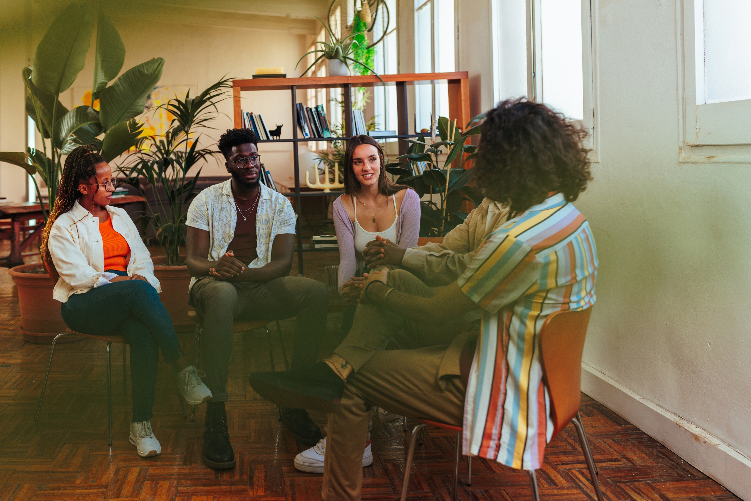 A group of five adults sit in a circle chatting during a therapy session