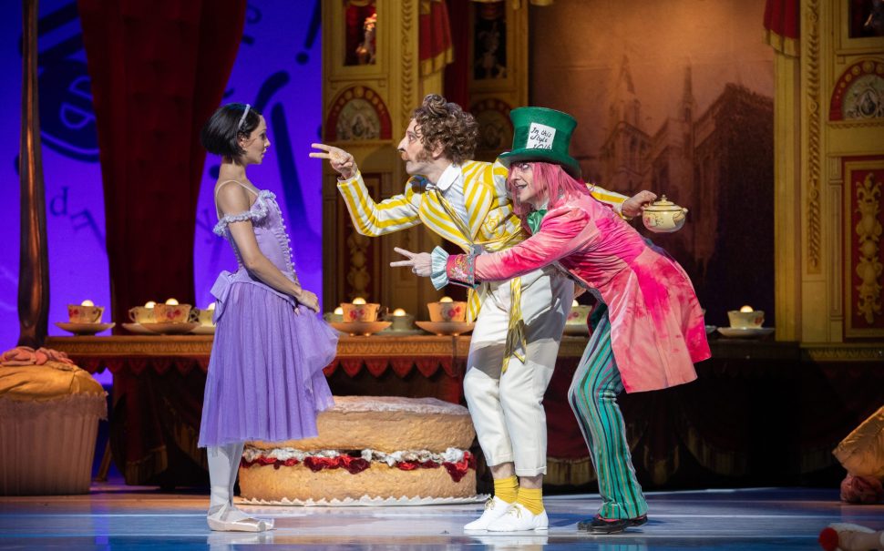 The Mad Hatter and the March Hare pointing at Alice onstage in the Royal Ballet's Alice's Adventures in Wonderland