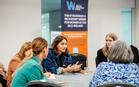 A panel of women sit around a table discussing business at the Women in Business & Tech event.