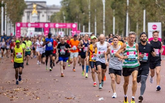 Runners race past the camera on The Mall. Buckingham Palace is in the distance.