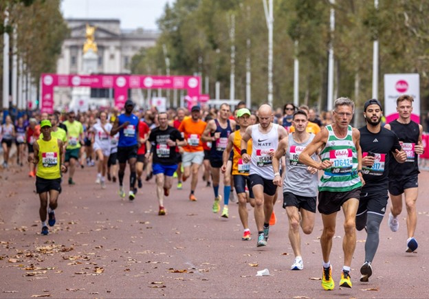 Runners race past the camera on The Mall. Buckingham Palace is in the distance.