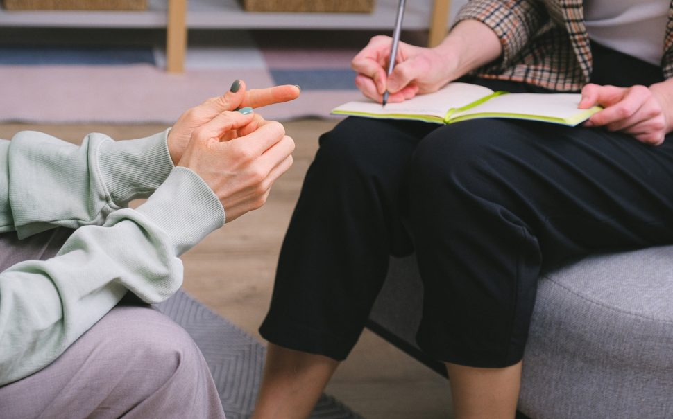 Woman writing in notepad during a therapy session