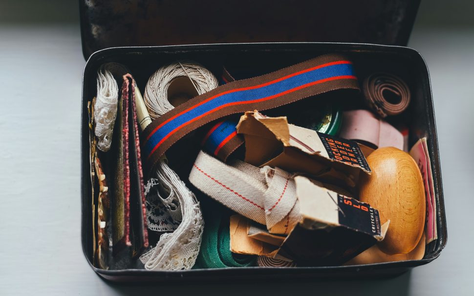 Vintage sewing box full of sewing tools such as twine and lace.