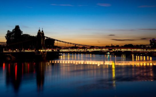 Hammersmith Bridge at sunset with lights over the river