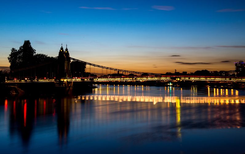 Hammersmith Bridge at sunset with lights over the river