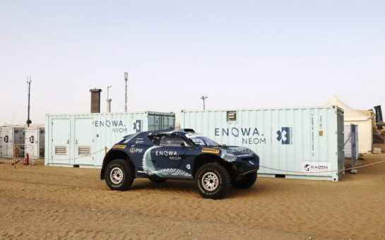 An Extreme E SUV next to two shipping containers all decorated with ENOWA branding, a partnership recognised by the sustainability nomination