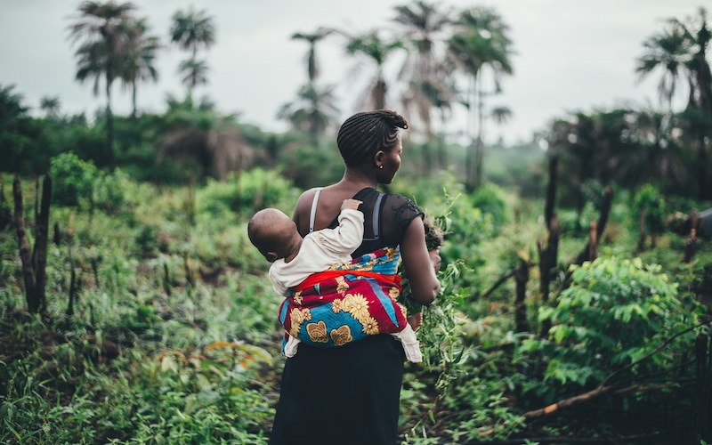 A woman with a baby strapped to her back.