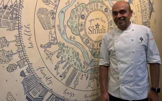 Chef Alfred Prasad, in this chef whites, stood next to a mural of Twickenham locations in Shiuli