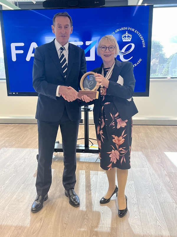 FACT CEO Kieran Sharp accepting the award from the presentation team. They are stood in front of a screen showing the FACT logo