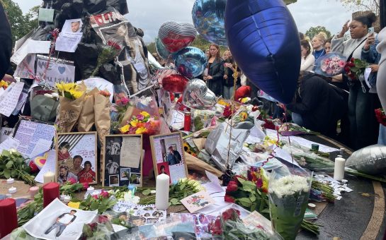 One Direction fans stood around the Peter Pan statue in Kensington Gardens, which is covered with flowers, letters and balloons