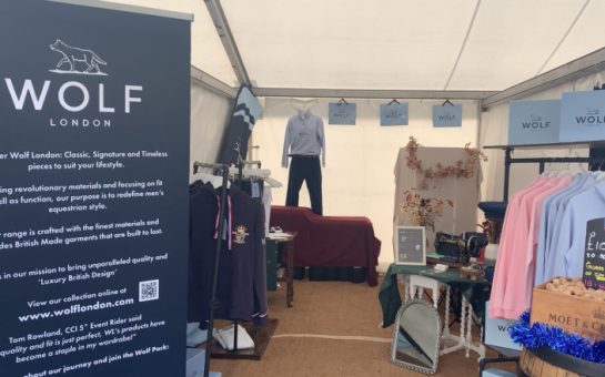 Wolf London's stand at Blenheim Horse Trials. The image shows an advertising board to the left, and clothing rails to the right and back.