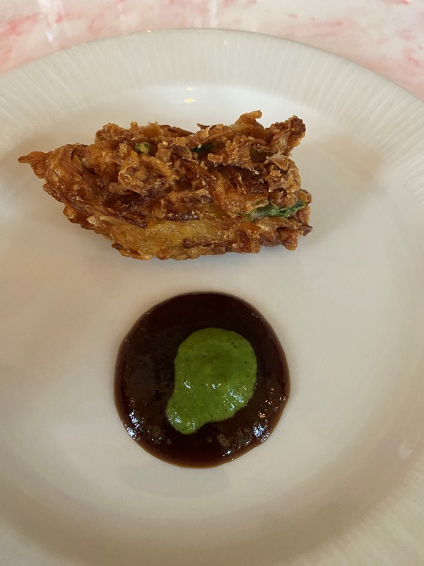 The samphire onion bhaji with a brown sauce topped with a green sauce