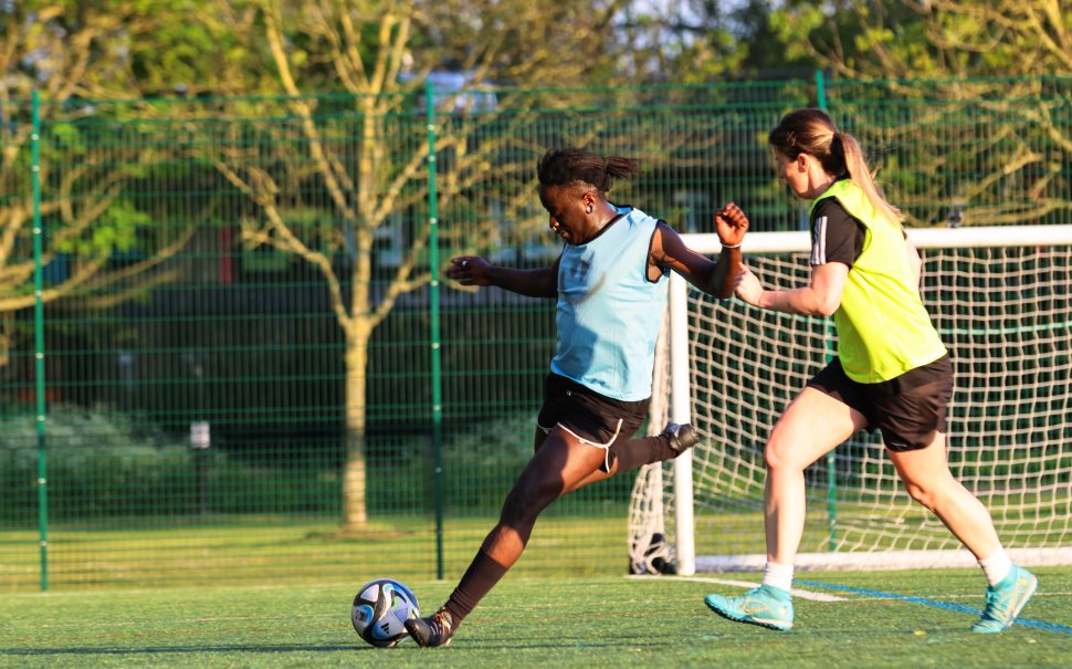 Two footballers from marginalised gender teams playing a match