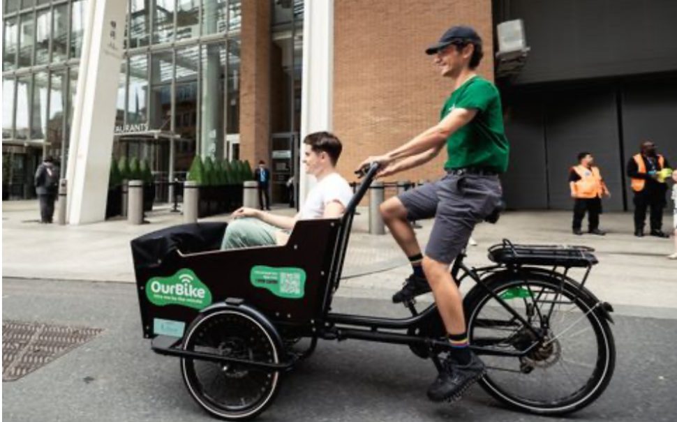 Douglas Leroy riding an OurBike with a friend inside