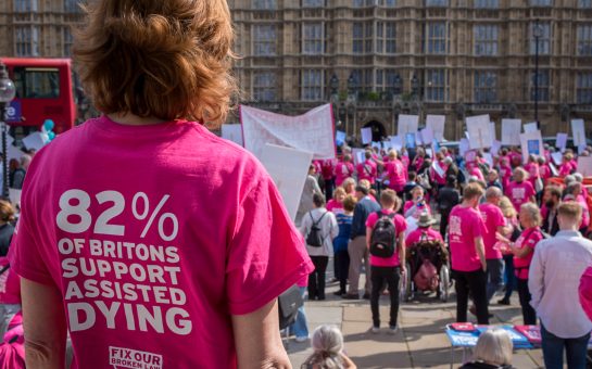 A photo showing supporters in colourful pink t-shirts gathered for an Assisted Dying Bill demo at the House of Commons.