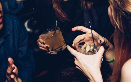 Two women talking while holding drinking glasses