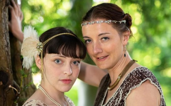 Actresses for Jay Gatsby and Daisy Buchanan with their heads close looking into the camera