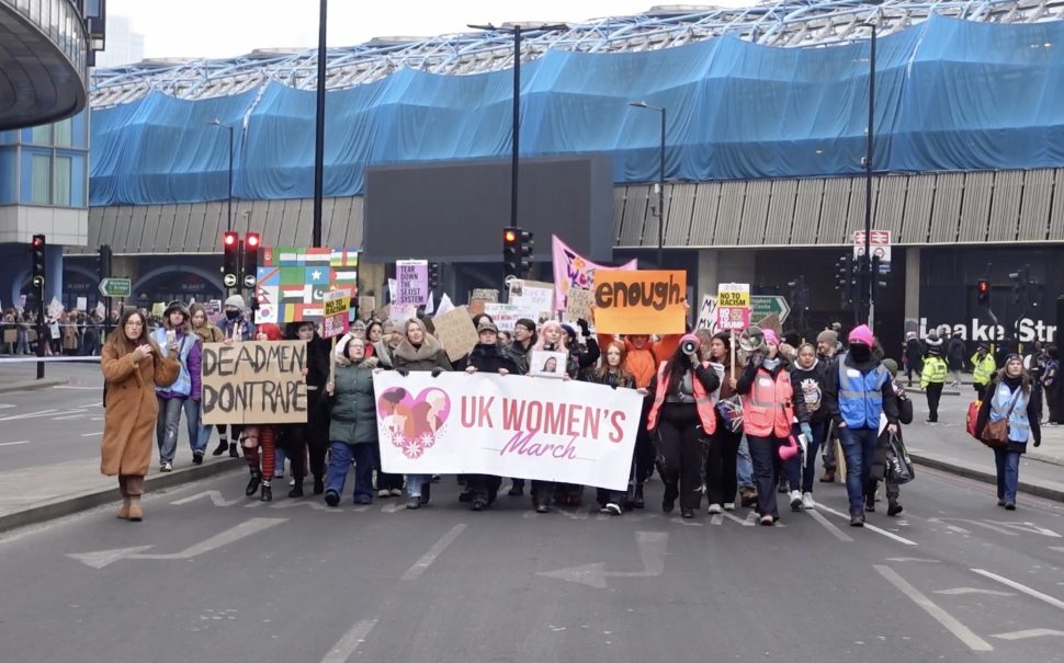 A group of protestors with signs and banners in the middle of the road