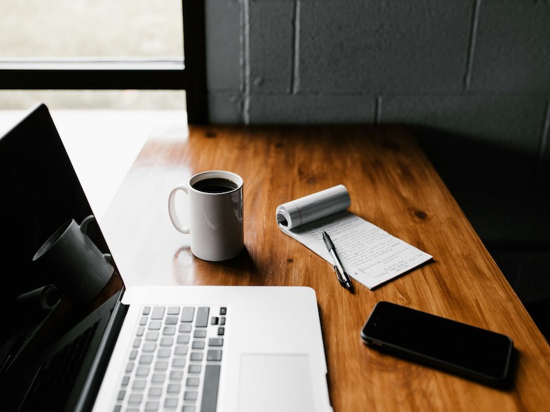 A photo of a computer, notepad and phone on a desk