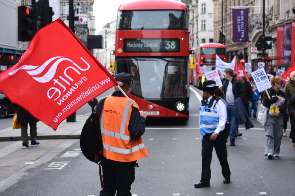 Man with flag stands in front of bus during street march for bus driver rights