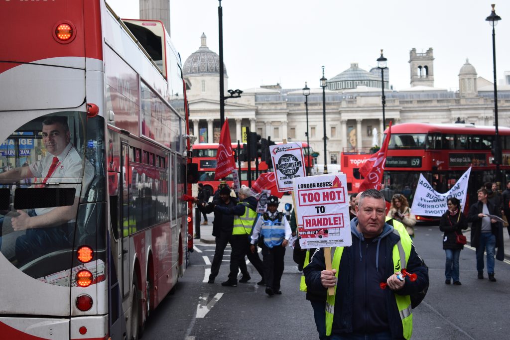 A group in support of bus drivers' rights march down Whitehall while some hand leaflets to drivers on the street