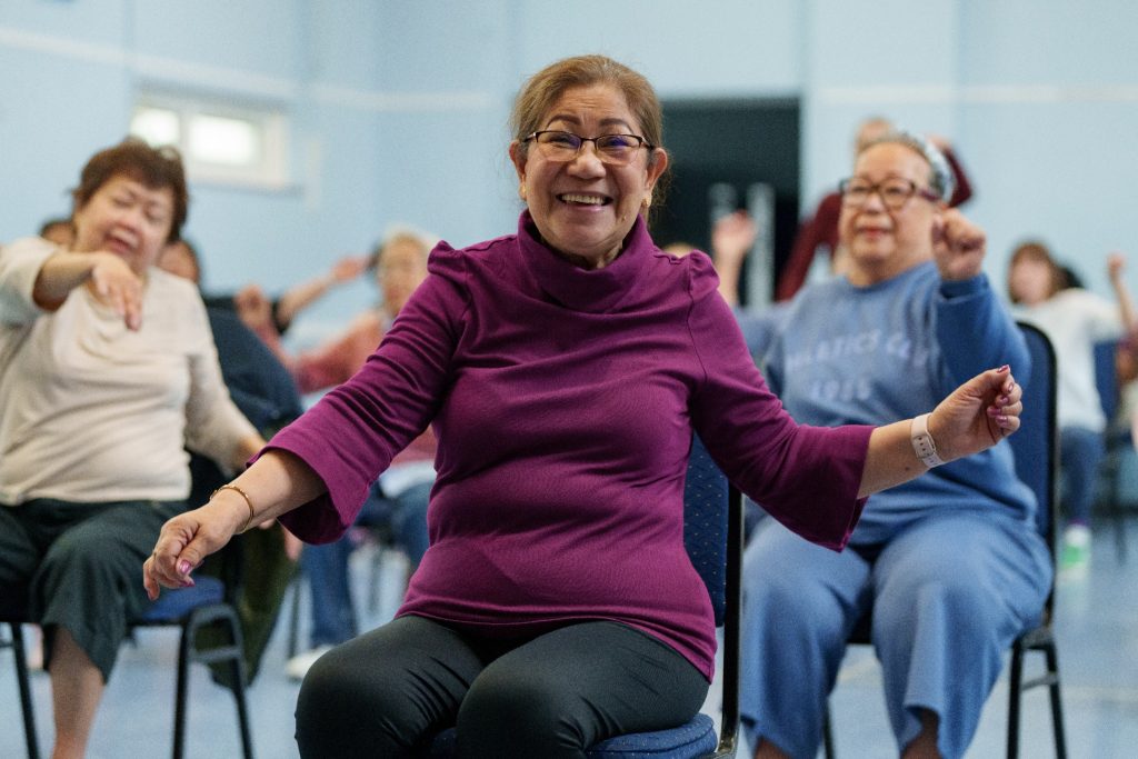 Smiling seated woman/Wimbledon Championships charity recipient with arms outstretched 